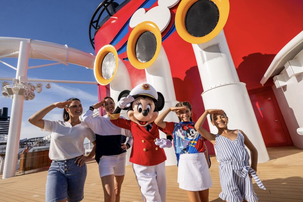 Personajes de Disney vestidos de marineros sonriendo a bordo de un barco de Disney Cruise Line